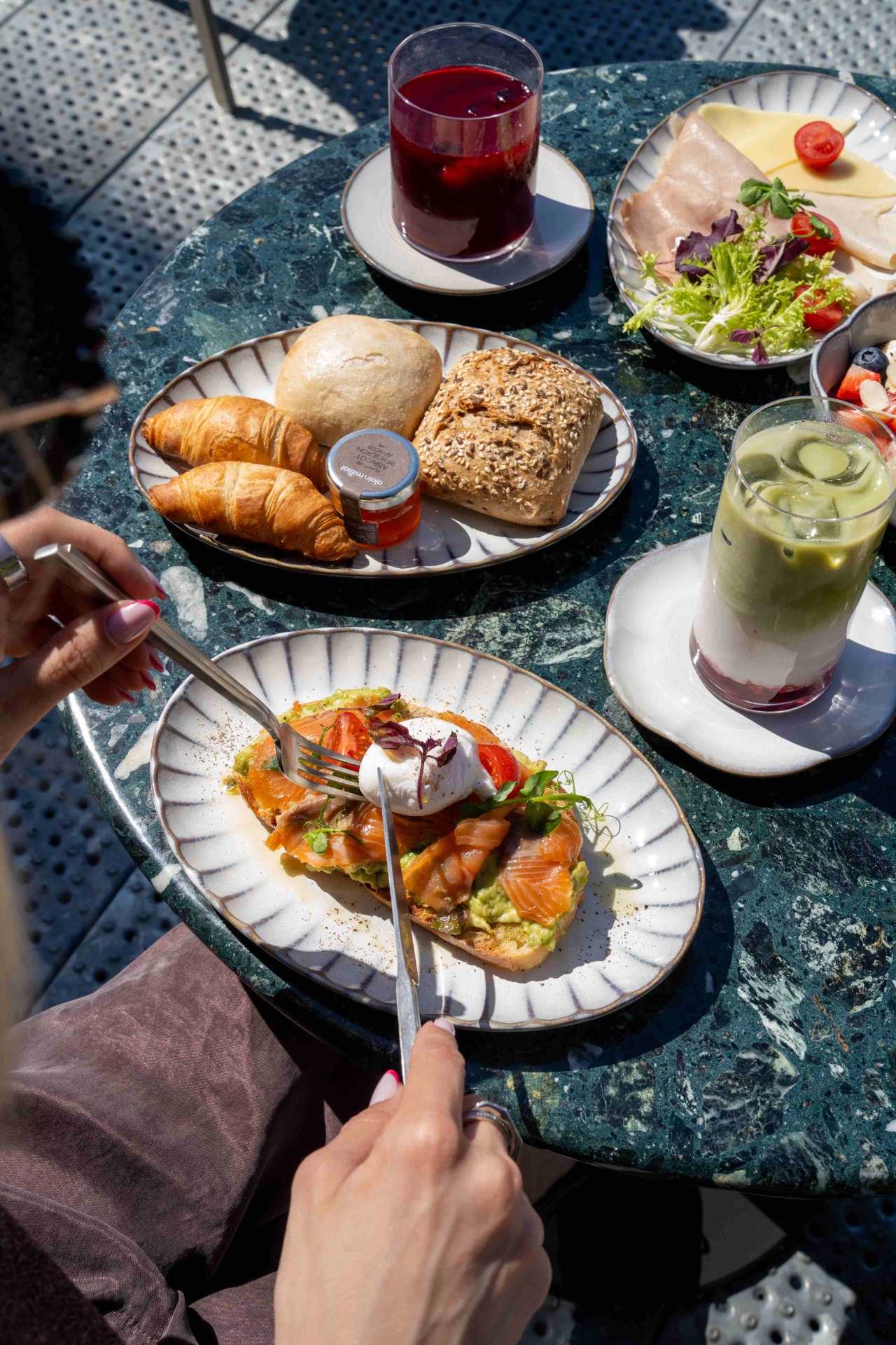 Brunch auf der Terrasse mit Lachs-Avocado-Toast, Croissants und Iced Matcha